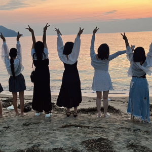 夕暮れの海辺に立つ子どもたち